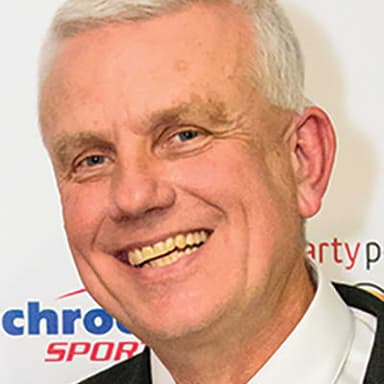 A man in a suit and tie smiling at the camera