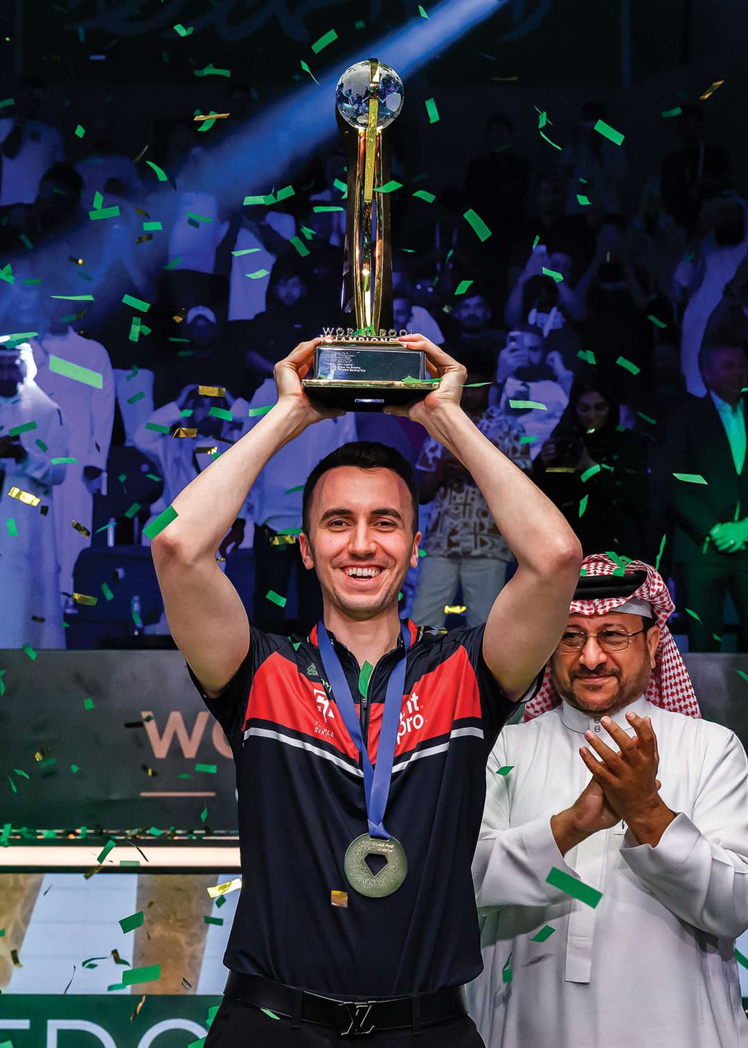 A man holding up a trophy in front of a crowd