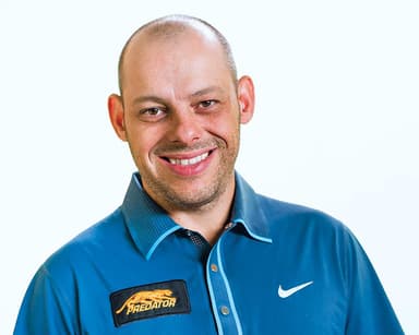 A man in a blue shirt smiling for a picture